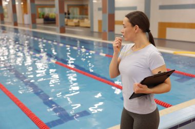 Kapalı havuzda düdük çalan bir yüzme koçu. Metin için boşluk