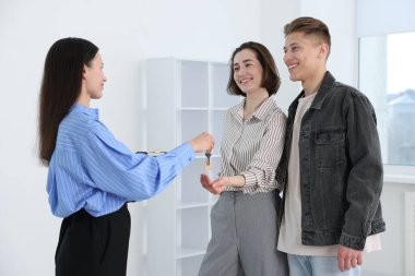 Emlakçı, evin yeni sahiplerine evin anahtarını veriyor.