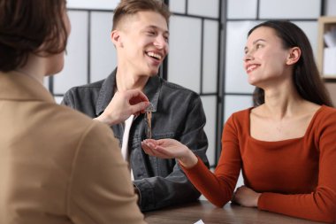 Emlakçı, evin anahtarını kapalı masa sahiplerine veriyor. Seçici bir odak noktası.