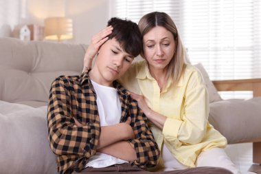 Anne üzgün oğlunu evde teselli ediyor.