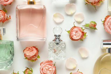 Düz kompozisyon, beyaz arka planda aromatik parfüm şişeleri ve güzel çiçekler vardı.