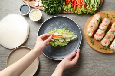 Gri ahşap masada nefis börek yapan bir kadın.