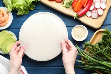 Mavi ahşap masada nefis börek yapan bir kadın.