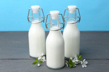 Taze süt ve çiçekler ahşap masada açık mavi arka planda