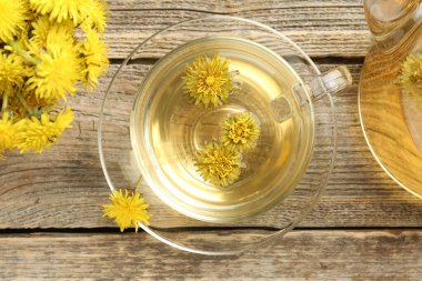 Tazeleyici karahindiba çayı ve çiçekler ahşap masada, düz yatıyordu.