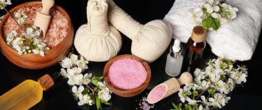 Siyah ayna yüzeyinde kozmetik ürünleri ve güzel çiçeklerle spa kompozisyonu