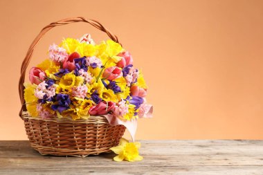 Mercan zeminine karşı ahşap masanın üzerinde güzel çiçekler olan hasır sepet. Metin için boşluk