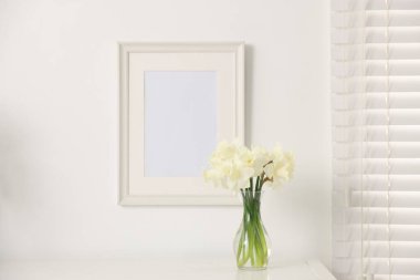 Evdeki beyaz masada vazodaki güzel nergisler.