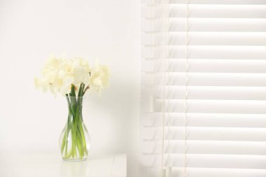 Evdeki beyaz masada vazodaki güzel nergisler, metin için yer.