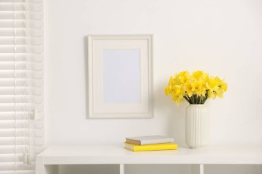 Vazodaki güzel nergisler ve evdeki beyaz dolaplarla ilgili kitaplar.