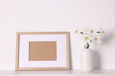 Vazodaki güzel nergisler ve evdeki beyaz masanın üzerindeki resim çerçevesi.