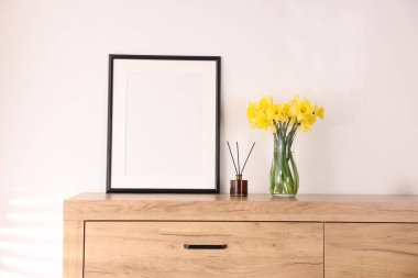 Vazodaki güzel nergisler, sazlıklar ve evdeki dolabın üzerindeki resim çerçevesi.