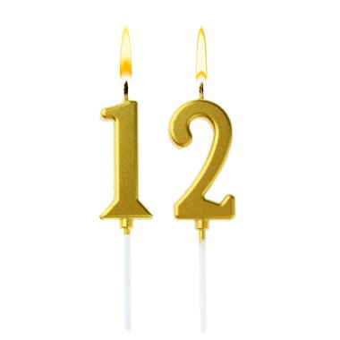 Beyaz arka planda 12 numarayı besteleyen altın pasta mumları yakıyor. Doğum günü veya diğer özel tarihler için şenlik dekorasyonu