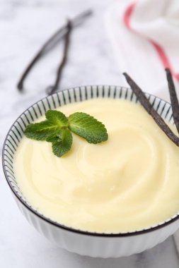 Lezzetli vanilyalı puding, nane ve kapsüller beyaz mermer masada, yakın plan.