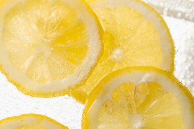 Arka planda limon dilimleri olan soda, yakın plan.