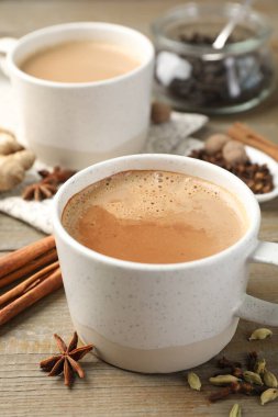 Ahşap masada fincanlarda ve baharatlarda Aromatik Masala çayı, yakın plan