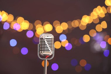 Karanlık arka planda bulanık ışıkları olan klasik mikrofon, mesaj için yer. Müzik ekipmanları