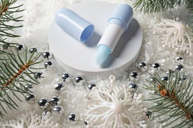Nemlendirici dudak kremi, Noel dekorasyonu ve yapay kar üzerindeki köknar ağacı dalları, yakın plan. Kış bakımı