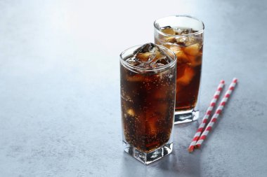 Kola bardakta buz ve açık dokulu masada pipetle tazeleniyor, yakın plan. Metin için boşluk