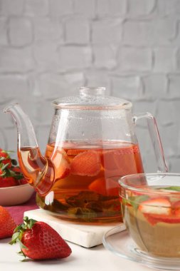 Aromatik çilekli meyve çayı ve beyaz masada nane şekeri, yakın plan.