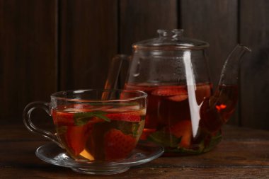 Çilekli Aromatik meyve çayı ve ahşap masada nane şekeri, yakın plan.