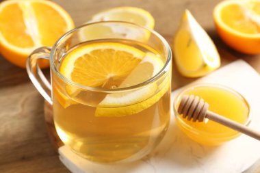 Cam fincanda aromatik meyve çayı, portakal, limon ve bal masada, yakın plan.