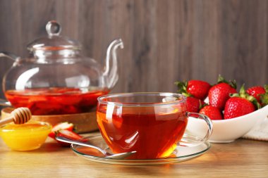 Çilekli Aromatik meyve çayı ve ahşap masada bal, yakın plan.
