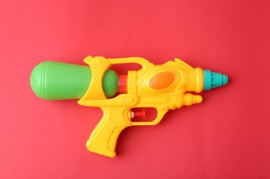 Kırmızı zemin üzerinde parlak plastik su tabancası, üst görünüm