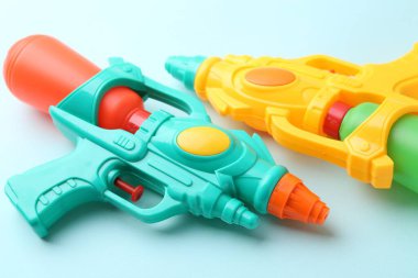 Açık mavi arkaplanda parlak plastik su tabancaları, yakın plan