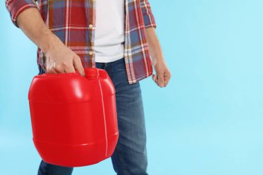 Açık mavi arka planda plastik kutu tutan adam, yakın plan. Metin için boşluk