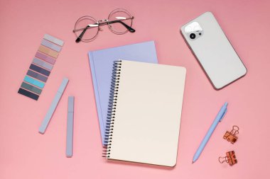 Pembe arka planda planlayıcı, akıllı telefon ve kırtasiye malzemesi, düz konum