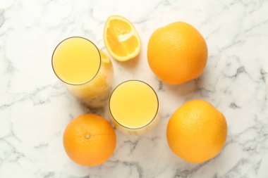 Bardakta portakal suyu ve beyaz mermer masada taze meyveler.