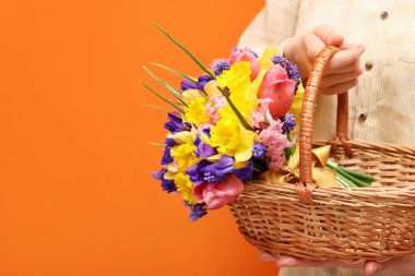 Turuncu arka planda güzel çiçekleri olan hasır sepetli bir kadın, yakın plan. Metin için boşluk