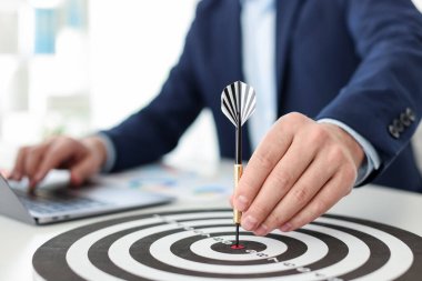 Dart oklu bir adam içeride çalışırken dart tahtasına nişan alıyor, yakın plan.