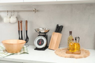 Retro mechanical kitchen scale and other utensils on white countertop indoors