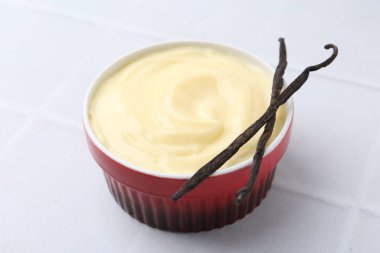 Lezzetli vanilyalı puding ve kapsüller beyaz fayanslı masa, yakın plan.