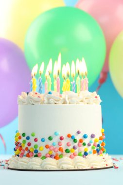 Nefis bento keki, serpiştirilmiş ve yanan mumlar mavi arka planda, yakın planda.