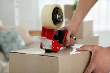 Karton kutuyu bantla kapatan adam içeride, yakın plan.