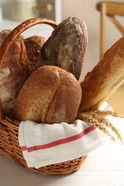 Farklı somunlar taze ekmek ve çiviler sepetin içinde beyaz ahşap masa, yakın plan