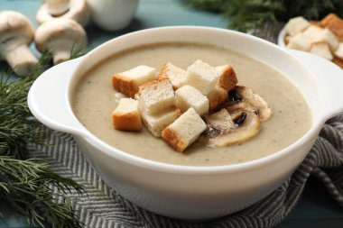 Lezzetli mantar kremalı çorba, kızarmış ekmek ve malzemeler mavi masada, yakın plan.