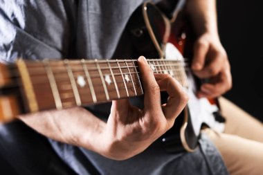 Siyah arka planda gitar çalan adam, ele odaklan.