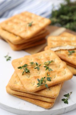 Beyaz masada kekikli lezzetli tuzlu krakerler, yakın plan.