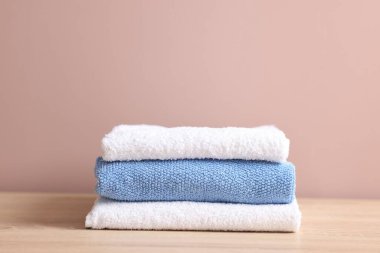 Tahta masadaki temiz havlular bej arka plana karşı, yakın plan