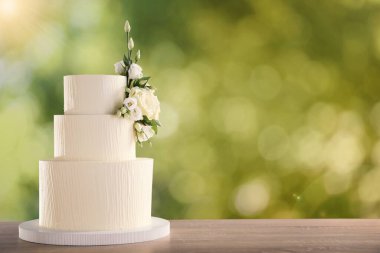 Dışarıdaki ahşap masada çiçeklerle süslenmiş güzel bir düğün pastası. Metin için boşluk