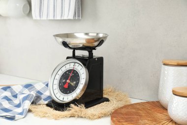Retro mechanical kitchen scale and other utensils on white countertop indoors