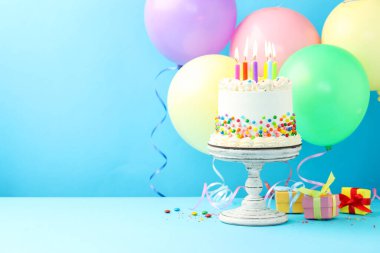 Renkli şekerli nefis bento keki ve açık mavi masada yanan mumlar. Metin için boşluk