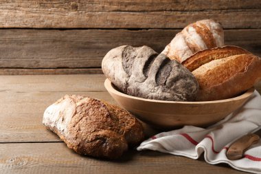 Tahta masada farklı somunlar taze ekmek ve bıçak.