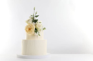 Masada beyaz arka planda çiçeklerle süslenmiş nefis bir düğün pastası. Metin için boşluk