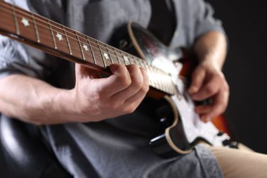 Siyah arka planda gitar çalan adam, ele odaklan.