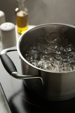 Kaynar suyla pişirme tenceresi ve soba gri arka planda, yakın plan